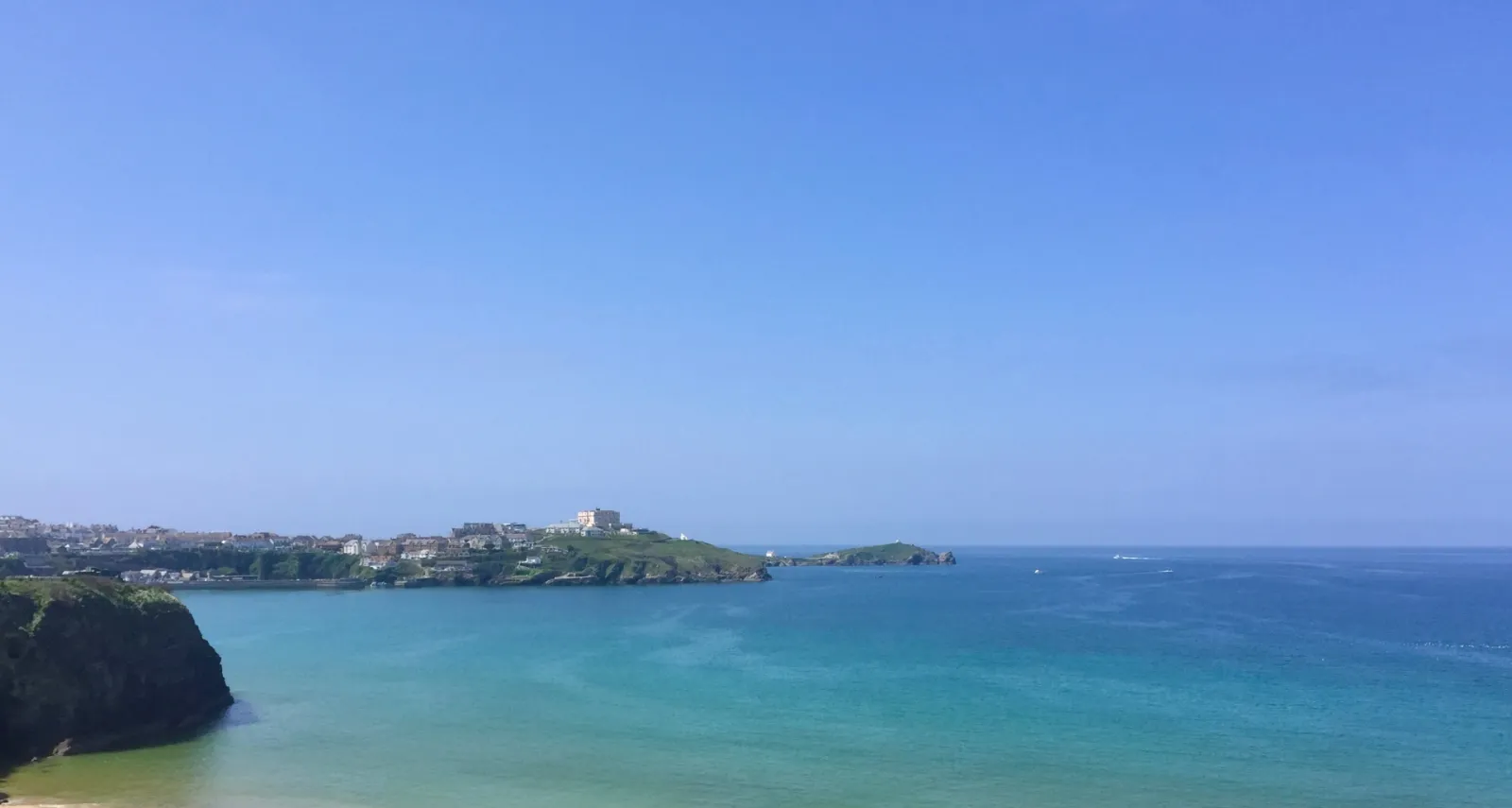 Newquay bay with turquoise sea and headland under a clear blue sky