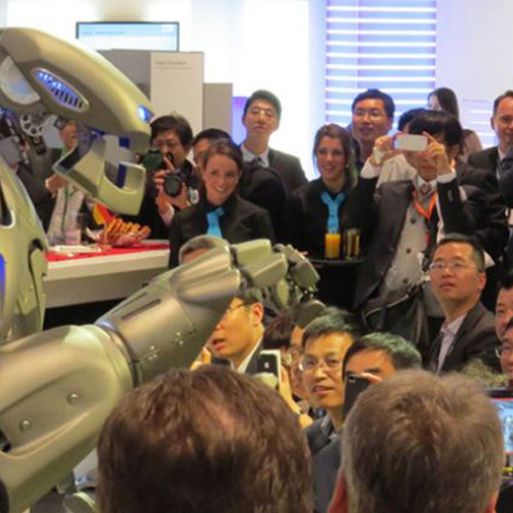 Titan the Robot performs to a crowd looking on in awe at the Siemens trade show stand.